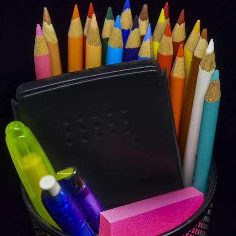 A pot of coloured pencils, pens and a calculator